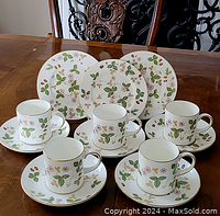 Five demitasse cups and saucers with matching small plates on wooden table