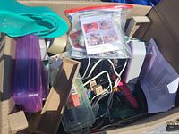 View showing assorted bin items including green flip-flop, purple and clear plastic containers, rolls of tape, cables and small wooden boxes, and zip-lock bag with photos.
