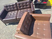 Brown two-seater sofa with tufted design, alongside a matching brown chair with similar tufted upholstery and armrests, placed outdoors on pavement.