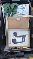 Top view of bin containing various frames and framed artwork showing the abstract black shape art and other pieces