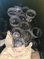 Top view showing 10 glass cylindrical vases forming a circle. Each vase has a rhinestone band around the rim. There is some beige packing paper at the corner.