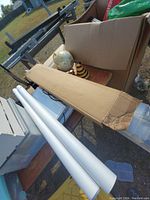 Photo showing lighting tubes, two globes, a yellow and black striped cone-shaped object, and black metal exercise equipment parts including a weight bar.