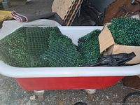 Bathtub filled with various greenery wall pieces in different shapes and sizes with plastic grid backing