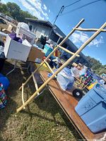 Wooden ladder leaning at an angle outdoors next to a table with various items.
