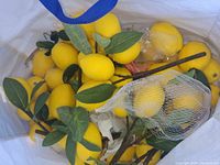 Artificial lemons attached to stems with green fabric leaves, bright yellow color.