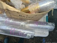 Box with stacks of clear plastic cups wrapped in plastic packaging.