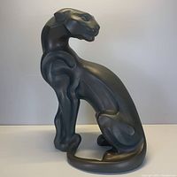 Full front and side view of black panther jaguar statue showing smooth stylized design and polished surface.