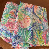 Photo of colorful twin size bedding items with mermaid and coral print pattern, showing pillowcase and fitted sheet folded.