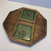 Top view of the octagonal hardwood serving board showing two green patterned square tile inserts and carved compartments.