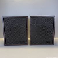 Pair of Realistic Minimus-3 speakers side by side, showing front fabric grill and wood-toned frame