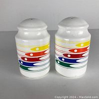 Front view of the two vintage ceramic salt and pepper shakers with rainbow pattern.