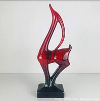 Front view of the tall red and black antelope statue with glossy finish placed on a flat surface.