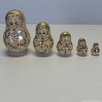 Set of 5 Russian nesting dolls lined up from largest to smallest on a plain background.