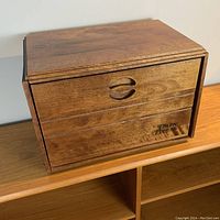 Solid wood bread box with carved handle and engraved 'Baribocraft Fresh Bread' branding on front panel. Medium brown wood with visible grain.