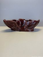 Side view of brown ceramic bowl with wave and leaf motif.