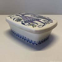 Side view showing the full ceramic butter dish with lid and floral/folk figure design.