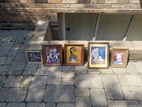 Photo showing all 5 framed pictures in Picasso style lined up on stone pavement outdoors.