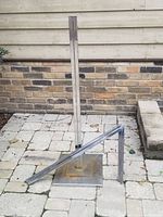 Side view showing the two vertical poles in chrome metal with holes for height adjustment and rust spots on the square flat base.