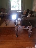 Photo showing the set of one coffee table and two end tables arranged in a living room with a couch and chair.