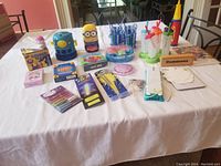 Full view of various kids items on table including games, bubble machine, popsicle molds, glow sticks, and craft supplies.