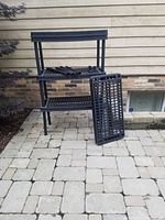 Front view of the assembled shelving unit showing two shelving levels and extra shelf panel leaning against it along with support poles on the shelves.