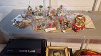 Photo showing a collection of More Charming Tails figurines mostly wrapped in plastic on a gray surface. Features various animal and nature themed designs and a bear pair on a red vehicle figurine on the right.
