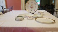 Photo displaying the full set of various china pieces including bowls, plates, cups, and serving dishes arranged on a table.