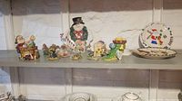 Shelf display of Charming Tales holiday figurines including a snowman with a wreath, elves, and animals, plus salt and pepper shakers in springtime designs