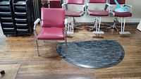 Vintage vinyl shampoo chair with metal arms and maroon vinyl upholstery surrounded by other salon chairs on wooden floor.