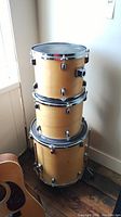 Stacked view of the three natural wood finish drums with Remo Weatherking Black Suede Emperor heads and chrome hardware.