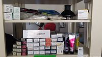 Photo of two shelves showing boxed hair pins, processing caps, cold wave paper, hair color tubes, and sample book