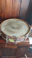Top view of vintage drum showing worn natural skin drumhead with heavy discoloration and patina.