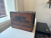 Side view showing Brewing Corporation of Canada Limited branding on brown wooden crate.