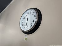 Wall clock showing front view, mounted on the wall with chrome rim and white clock face.
