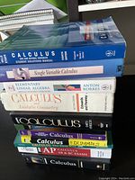 Top view of stacked calculus and math related textbooks showing titles and bindings.