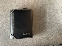 Black Baellerry leather wallet closed showing front with logo and cream stitching