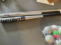 Two aluminum baseball bats, a Louisville Slugger and an Easton, with a small bag containing various baseballs and practice balls.