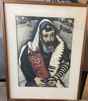 Photo of framed print depicting a Jewish religious figure holding a Torah scroll with Star of David, in traditional attire, in wooden frame.