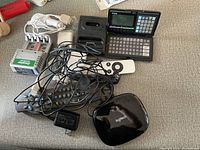 Photo showing mixed electronics, including Casio electronic dictionary, Logitech mouse, and cables.
