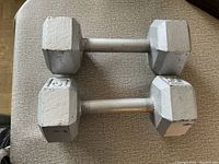 Pair of 15 lb hexagonal dumbbells shown on a beige textured surface, displaying paint wear and metal handles.