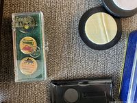 Plastic case containing three colorful golf ball markers with Hawaiian themes.