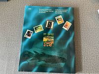 The cover of a teal coloured album entitled 'Souvenir Collection of the Postage Stamps of Canada 1991' showing six Canadian postage stamps and a fish illustration.