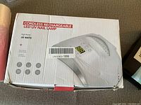 Photo of the box for a cordless rechargeable LED UV nail lamp, showing model and wattage.