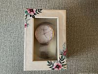 Victoria Hyde London women's watch inside decorative floral box showing front view of watch face and band.