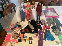 Overview of four dolls, clothing pieces, shoes and accessories on table