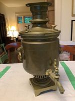 Front view of large heavy brass samovar showing handles, spigot, and lid configuration.
