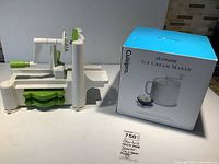 White Donvier manual ice cream maker in original box with blue lid and mixing paddle visible