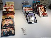 Top down view showing three groups of DVD box sets arranged on a white surface: CSI Miami sets, Curb Your Enthusiasm sets, and Dexter plus other series sets