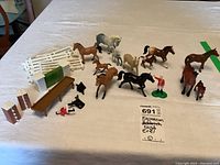 Photo showing the full set of about 13 Ertl equestrian toy items including model horses, rider figures, fences, and accessories arranged on a table.