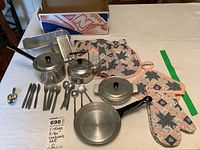Photo of vintage kids metal cookware set with fabric accessories displayed on table, showing all items clearly.